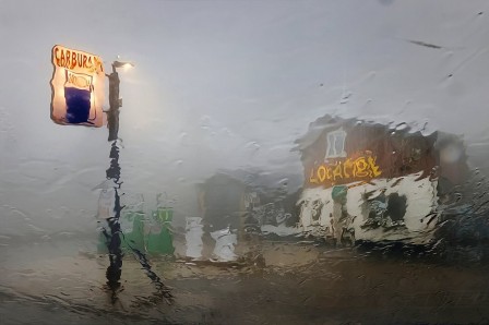 la vision floue d'une station d'essence à travers la vitre d'une voiture noyée sous la pluie