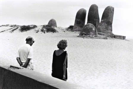 un couple face à une main géante émergeant du sable