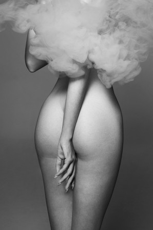 une femme nue dans les nuages, la main droite dans son dos entre les fesses