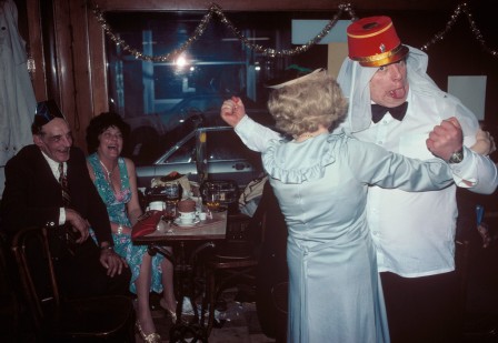 assis dans un café, un couple en regarde un autre danser déguisé