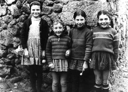quatre petites filles en jupe et chandail posent avec le sourire devant un mur en attendant la révolution