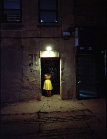extérieur nuit : une femme en robe jaune entre au numéro 39 de la rue