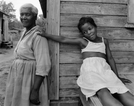 une petite fille noire, la main posée sur l'épaule de sa grand-mère
