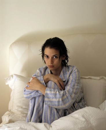 Winona Ryder assise dans son lit en pyjama rayé