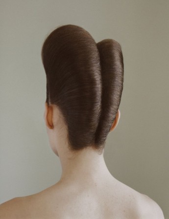 une femme de dos, deux vagues de cheveux séparées par un trait central descendant jusque sur la nuque